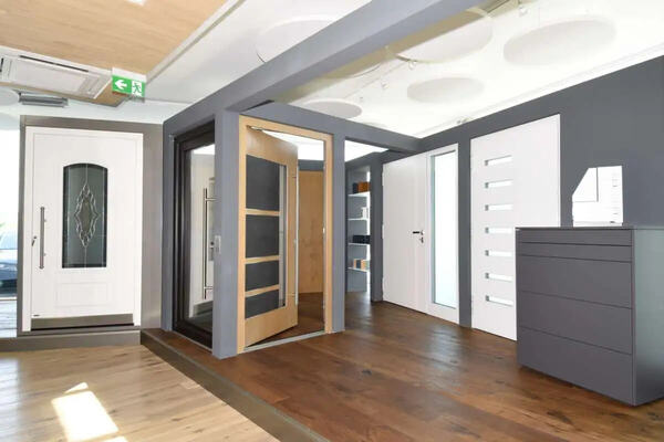 Moderne Türenausstellung mit verschiedenen Haustüren auf hellem Holzboden im Showroom.