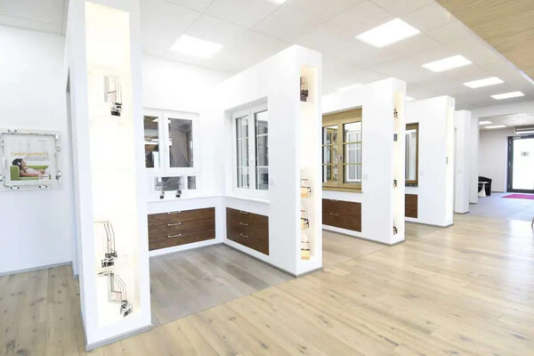 Moderner Ausstellungsraum mit Fenster- und Türmodellen, hellem Holzfußboden und Beleuchtung.