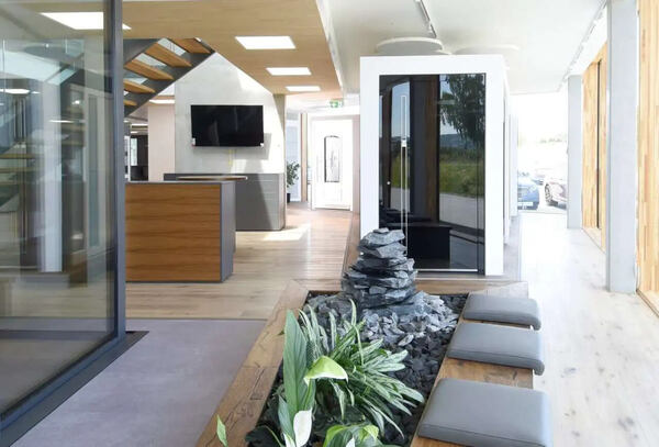 Modernes Büro mit Holztreppe, Pflanzen, Steingarten und großen Fenstern für Tageslicht.